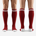 Full-length pair of custom dark red and white knee-high soccer socks laid flat showing complete colorway