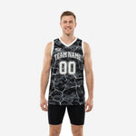 Custom digital camo basketball jerseys in black and white with cracked-earth overlay, team name arc and front number shown on male model - front and back view