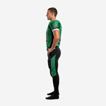 Side view of green and black sublimated football uniform showing black angled shoulder panel, green jersey body, and full-length green side panel on black football pants