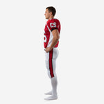 Reverse side view of red and white American football uniform set showing side panel construction and pant stripe alignment on white football pants