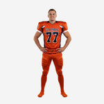 Custom football uniform sets in orange and navy with navy shoulder panel, V-neck collar, front number 77, team name arc, and matching orange pants with navy side stripe - front view