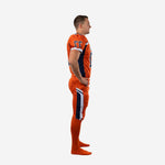 Side view of orange and navy custom football uniform sets showing navy shoulder-to-side panel on jersey and matching navy and white outer-thigh stripe on football pants