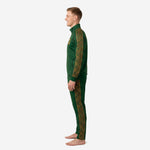 Custom 2-piece soccer tracksuit in forest green and old gold worn by adult male model showing tapered pant fit and stand collar jacket construction