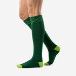 Forest green soccer socks with lime green accent panels and geometric cuff knit, angled side view on male model