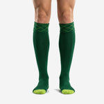 Custom forest green soccer socks with lime green toe panel and diamond argyle cuff pattern, front view on male model