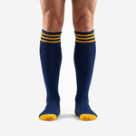 Custom gold soccer socks with Navy Blue body and three Athletic Gold stripes at the ribbed cuff, front view on adult male model