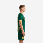 Green soccer uniforms side view left showing athletic gold leaf graphic across jersey and shorts
