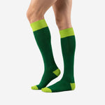 Green soccer socks in Forest Green and Lime Green colorblock design, three-quarter angle view on male legs