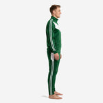 Custom green soccer tracksuit side view showing twin white stripes down sleeve and tapered pant leg on male model