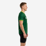 Custom green soccer training jersey side view showing Forest Green body with Lime Green panel and contrast sleeve cuff trim, adult male model