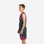 Side view of charcoal grey youth basketball uniform set showing hot-pink armhole binding and shorts hem trim detail