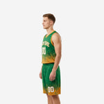 Side view of custom kelly green and gold basketball uniform set showing jersey hem gradient blending into gold and matching shorts with side split hem