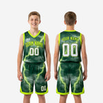 Detail view of green lightning youth basketball shorts showing neon lime hem trim, side split, elastic drawcord waistband, and sublimated player number