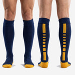 Custom knee high navy blue soccer socks with Athletic Gold accent, full pair shown on adult male model