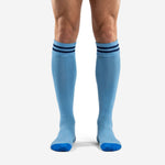 Custom light blue soccer socks with navy double-stripe ribbed cuff, front view on adult male model