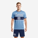 Custom light blue soccer uniform front view showing powder-blue jersey with navy colorblock panel, white trim, and matching navy shorts