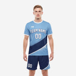 Custom light blue soccer uniform with navy blue diagonal colorblock jersey and matching navy shorts, front view on male model