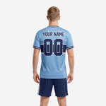 Light blue soccer uniform jersey detail showing geometric hex-weave pattern, navy mid-chest number panel, and crew neck collar tipping