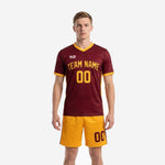 Custom maroon soccer uniforms front view showing Athletic Gold V-neck trim, team name, and number on 100 percent polyester jersey and matching shorts