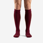 Custom maroon soccer socks with Athletic Gold side stripe and ribbed cuff, front view on male model