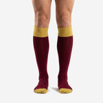 Custom maroon soccer socks with Athletic Gold ribbed cuff and toe box, front view on male model