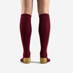 Full-length view of custom maroon and gold soccer socks over the calf on adult male model