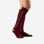 Custom maroon soccer socks showing full-length Athletic Gold calf stripe and Gold heel block, left side view