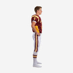 Side view of custom maroon and gold youth tackle football uniform showing sleeve number, gold lower side panel, and maroon-gold double side stripe on white pants