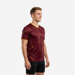 Maroon soccer training jersey with gold marble sublimation print and gold V-neck trim, left side view on male model