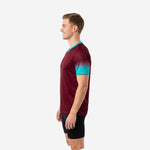 Maroon soccer training jersey with teal gradient short sleeves and V-neck trim, opposite side view on male model