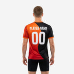 Detail view of custom mens soccer practice jersey showing white team name and number on black and orange sublimated chest panel