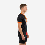 Mens soccer practice jersey in black and orange sublimated colorblock design, left side view showing V-neck and sleeve cuff trim