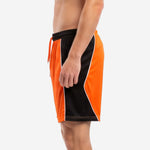 Right side view of custom mens soccer shorts displaying orange and black colorblock construction with elastic drawcord waistband