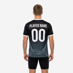 Close front angle of custom mens soccer training jersey showing team name, player number, and gradient fade from black to charcoal