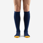 Custom navy blue soccer socks with athletic gold side piping and toe box, front view on adult male model