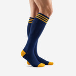 Custom navy blue soccer socks with gold stripe cuff band and gold heel toe panels, side profile view on adult male model