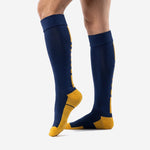 Knee high custom navy blue soccer socks with Athletic Gold contrast zones, back angle view on adult male model