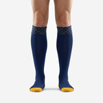 Custom navy blue soccer socks with Athletic Gold diamond geometric cuff band and gold toe block, front view on adult male model