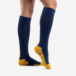 Custom navy blue soccer socks showing Athletic Gold heel cup and side dot accent pattern, side view on adult male model