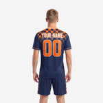 Close front detail of custom orange soccer uniform with arched team name and front number on navy body