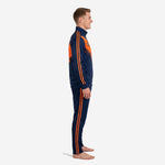 Custom navy and orange soccer tracksuit side view showing full-zip jacket and tapered pants with dual orange sleeve stripes on male model