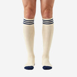 Custom navy and white soccer socks front view showing cream ivory body with 3-stripe navy cuff band and navy toe contrast on adult male model