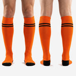Custom orange and black soccer socks full length view from cuff to toe on adult male model