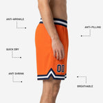 Close-up detail of the navy and white chevron V-notch hem stripe on custom orange basketball shorts showing sublimated color depth