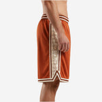 Side view of custom orange basketball shorts showing full-length cream geometric hexagonal panel with double brown pinstripe border and chevron hem