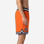 Side view of custom orange basketball shorts showing V-notch chevron hem detail, navy and white stripe trim, and elastic waistband with internal drawcord