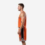 Side view of the orange and black basketball uniform showing black side panel on jersey and chevron hem detail on shorts leg