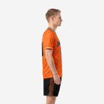 Custom orange and black soccer uniform left side view showing white sleeve trim and black shorts with orange side panel
