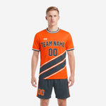 Custom orange soccer uniform with charcoal diagonal stripe panels and matching charcoal shorts, front view on male model