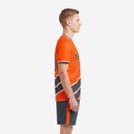Orange soccer uniform side view showing diagonal charcoal stripe design and charcoal shorts with orange side stripe